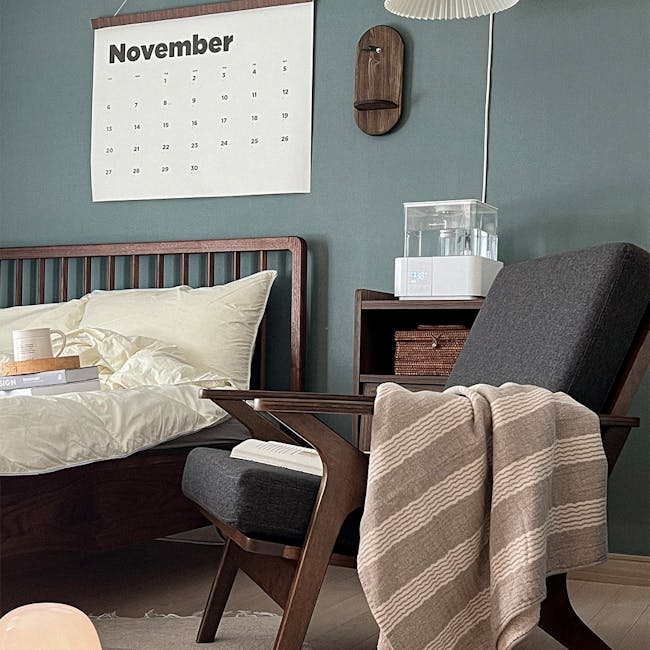 Aston Armchair - Seal - 14 - Wooden nightstand, white calendar, blue wall, wooden chair, beige blanket, gray cushion, wooden