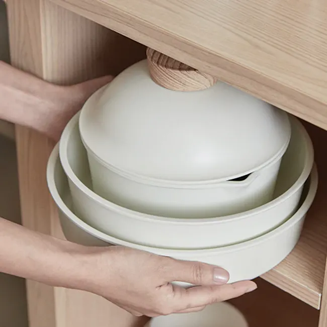 Sodam Nonstick Cookware Set - Cream White - 4 - White ceramic dish, wooden drawer, person's hands, kitchen utensils, dish