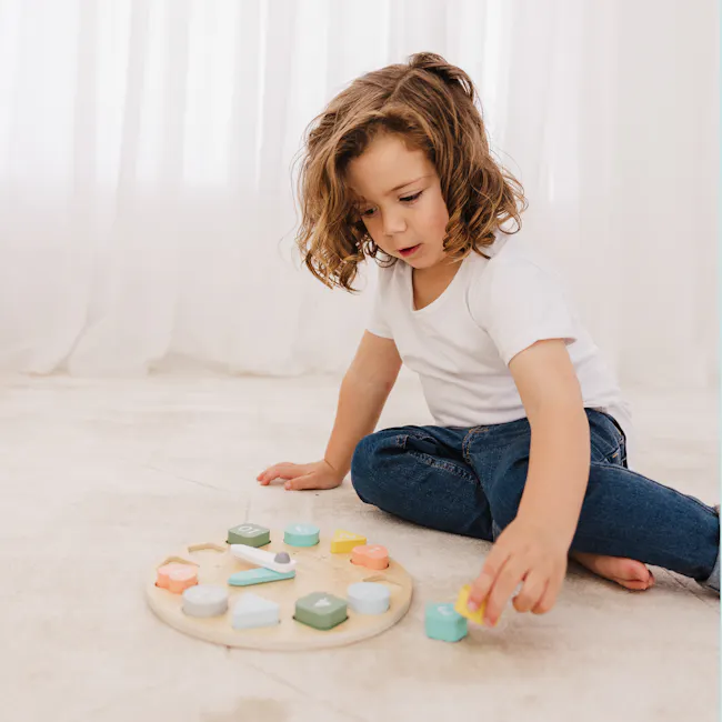 Bubble Wooden Clock with Shapes - 6 - Child playing on carpet, young girl sitting, colorful toys, wooden board, white