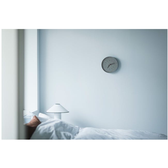 Essent Clock - Gray - 6 - Minimalistic bedroom with a modern clock, White bedding and light blue walls, Single bedside lamp