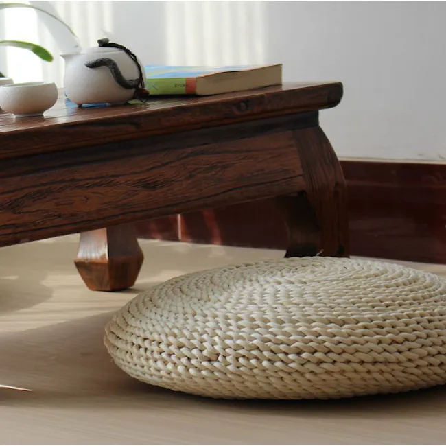 Ezra Floor Cushion - 2 - Wooden table, natural light, indoor setting, textured surface, rustic charm, woven stool