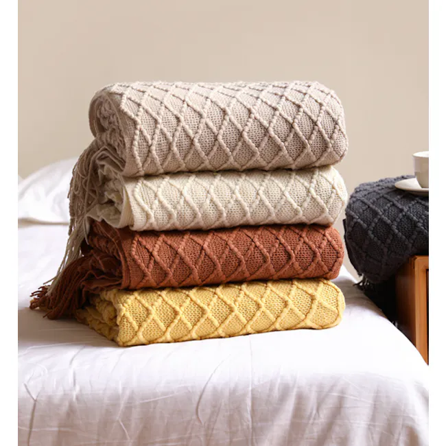 Hanako Knitted Throw - Burnt Orange - 6 - Soft, knitted blankets stacked on a bed, featuring a mix of beige, cream, brown
