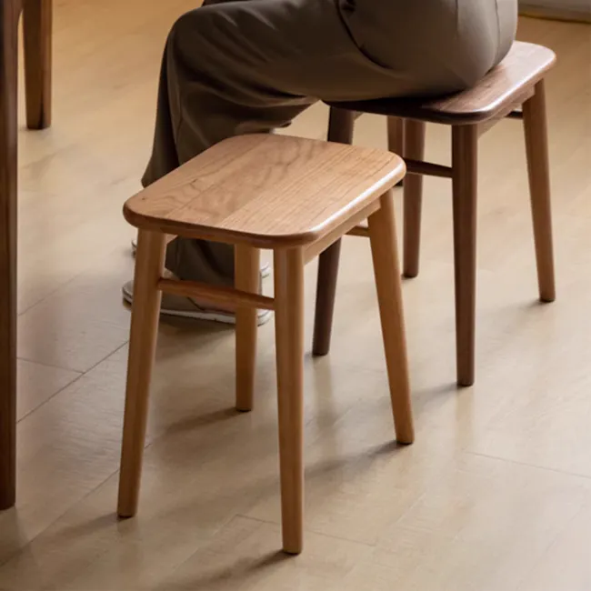 Haku Stool - 5 - Wooden stool, minimalist design, light brown finish, wooden legs, person sitting, casual attire, brown