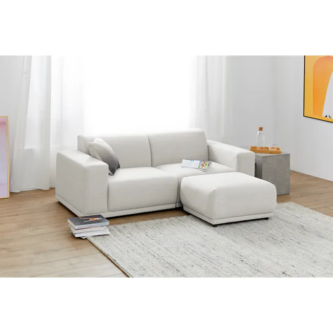 Milan Ottoman - Ivory (Fabric) - 5 - Light-colored sofa, minimalist decor, soft lighting, white curtains, wooden floor