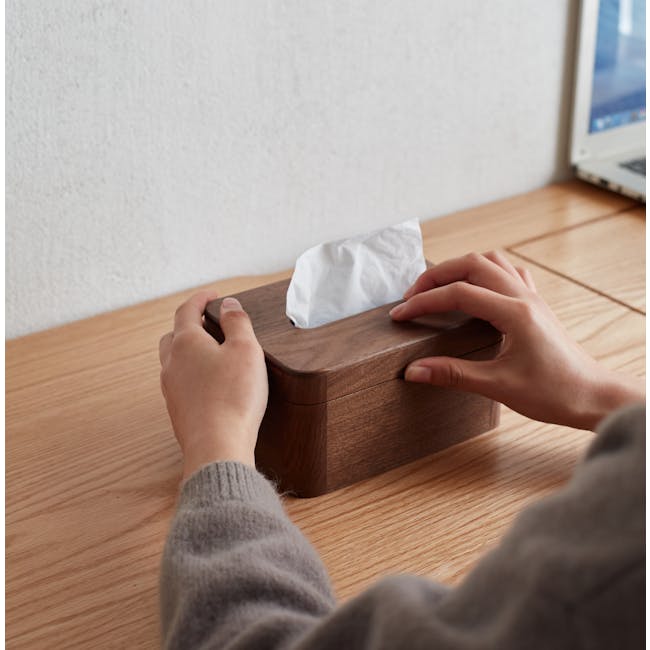 Kenji Tissue Box - 9 - Wooden box, person's hands, white tissue, wooden surface, gray sweater, wooden desk, laptop in