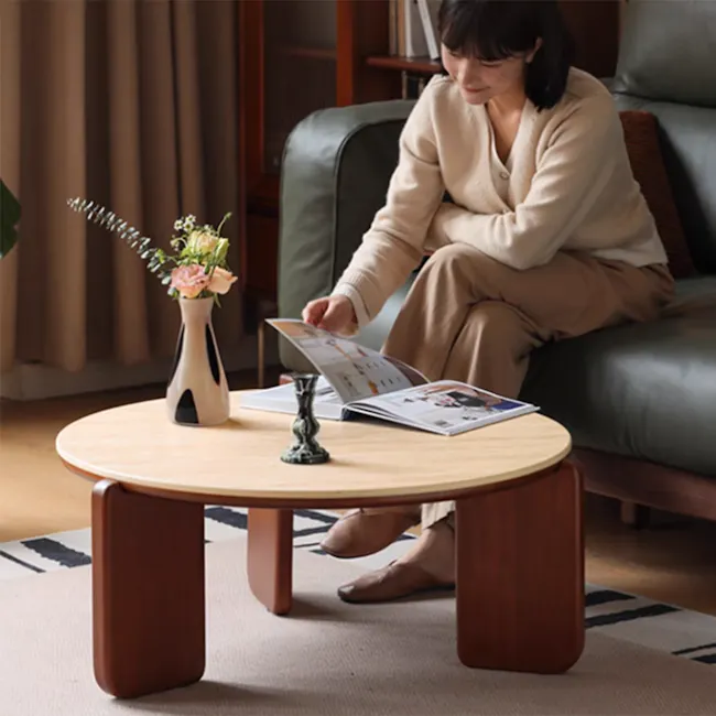 Blair Round Coffee Table - Travertine (Sintered Stone) - 12 - Sitting on a dark leather sofa, woman in beige sweater and