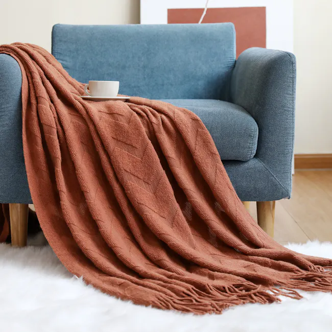 Hikari Chevron Knitted Throw - Caramel - 2 - Soft, cozy blue armchair, plush white rug, rust-colored throw blanket, cozy