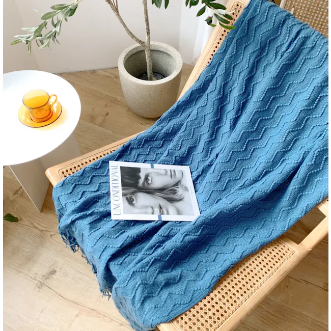 Havre Throw - Grey - 5 - blue textured blanket, cozy lounge chair, wooden floor, white side table, orange cup, green plant