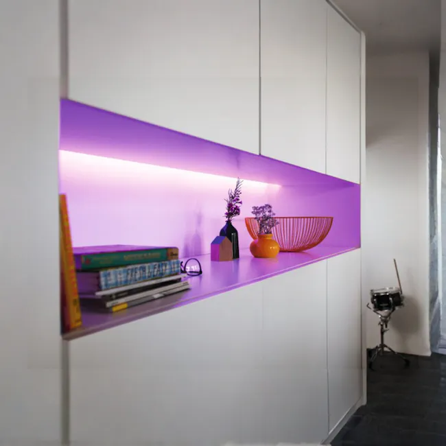 Philips Hue V4 Lightstrip Plus - 3 - Shelf with vibrant purple backlight, modern shelving unit, books, decorative items