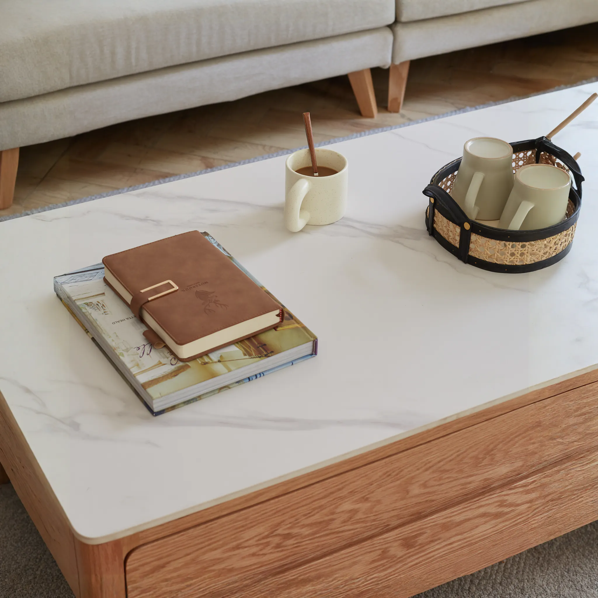 Devin Coffee Table 1m (Sintered Stone) - 21 - White marble coffee table, beige sofa, wooden floor, brown leather notebook
