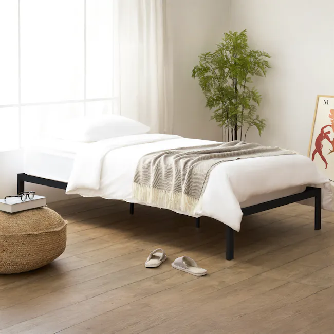 Yves Single Metal Divan Bed - Black - 2 - White bed with black frame, beige and gray striped blanket, wooden floor, natural