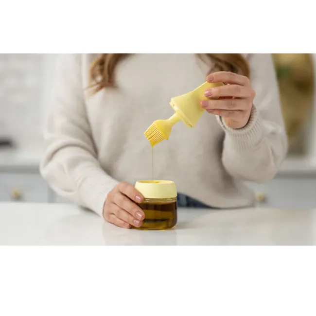 Zuutii Oil Dispenser with Brush - Lemon Yellow - 5 - woman pouring honey from a jar, kitchen countertop, natural light