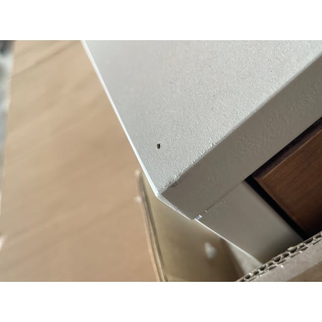 (As-is) Brexley Coffee Table - 10 - Small hole on textured surface, Wooden panel beside white surface, Cardboard box near