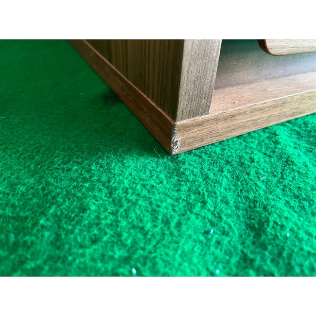 (As-is) Herta Tall Sideboard 1.2m - Walnut - 1 - 16 - Wooden leg on green carpet, close-up view, corner of wooden structure